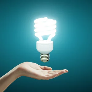 Lampadina a risparmio energetico accesa sopra una mano aperta